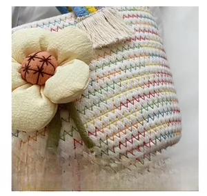Macro dettaglio di borsa in paglia bianca intrecciata con fiore 3D e cuciture arcobaleno