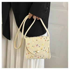 Dettaglio di una borsa a busta intrecciata crema con fibbia a perla e ricamo colorato