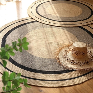 Detail of round hand-woven cotton and jute rug with spiral texture on wooden floor
