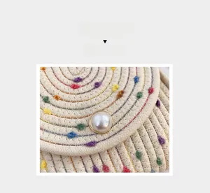 Dettaglio della borsa in cotone intrecciata a mano con pompon colorati e bottone di perla