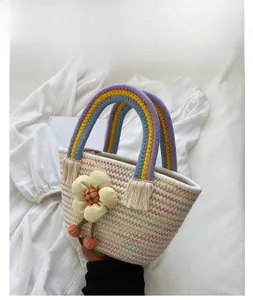 Dettaglio dei manici arcobaleno e fiore in tessuto sulla borsa in paglia intrecciata