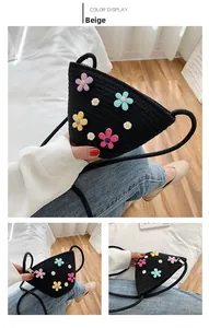 Détail d'un sac en paille noire avec broderies de marguerites 3D colorées et zip