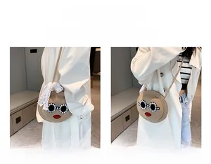Detail view of round woven straw bag with cartoon sunglasses, lips, and lace bow