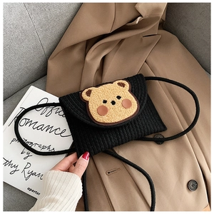 Detail of a black corduroy mini crossbody bag with a 3D plush bear on a blazer background
