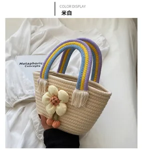 Dettaglio di borsa in paglia beige con manici arcobaleno e decorazione floreale