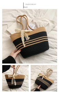 Detail of color-block straw tote bag with black stripes and cream lace bow accent