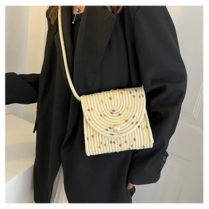 Dettaglio della borsa intrecciata color crema con punti colorati e chiusura in perla