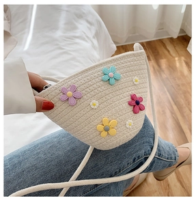 Détail d'un sac bandoulière en paille demi-lune orné de fleurs colorées en 3D