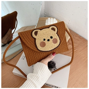 Detail of hand-woven envelope bag with a cute 3D teddy bear patch and a thin shoulder strap