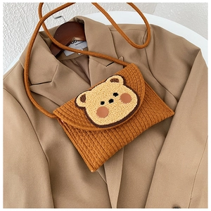 Detail of a brown woven envelope bag with cute 3D cartoon bear patch on a khaki blazer