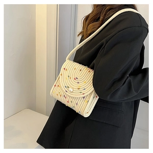 Vista laterale dettagliata della borsa a tracolla intrecciata crema con pompon colorati