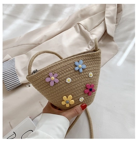 Détail d'un sac seau en paille fait main avec des appliques florales et une fermeture éclair