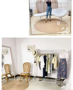 Detail view of woven rattan floor mat showcased alongside stylish summer apparel and racks
