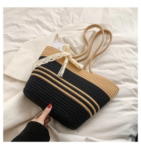 Close-up of handmade woven beach bag with black stripes and white lace bow detail