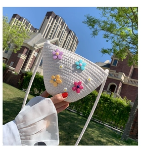 Gros plan d'un sac bandoulière en paille avec des fleurs 3D colorées dans la nature