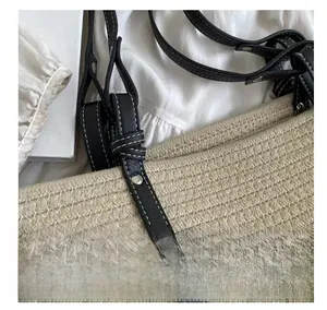 Close-up of woven cotton bucket bag featuring black leather handles and silver rivets