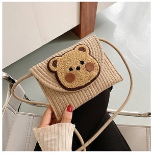 Close-up of khaki corduroy mini bag with cute teddy bear patch and woven shoulder strap