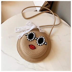 Detailed close-up of a round woven straw bag featuring pearl sunglasses and red lip embroidery