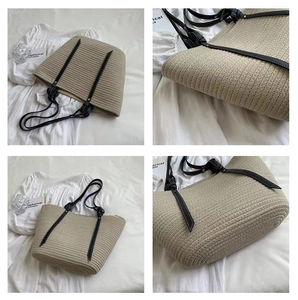 Detail view of beige woven cotton bucket bag featuring sleek black shoulder straps and textures