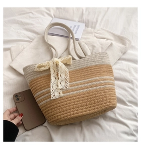 Close-up of woven straw tote bag featuring brown stripes and a delicate lace bow decoration