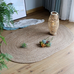 Oval braided jute area rug in natural wood tones for bedroom and hotel decor