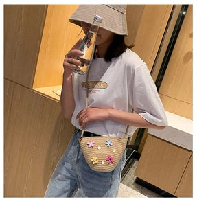 Détail d'un sac bandoulière en paille tressée orné de fleurs 3D colorées