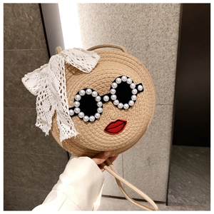 Detail of round straw bag with pearl sunglasses, red lips embroidery and lace bow