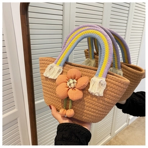 Dettaglio borsa in paglia con fiore arancione e manico intrecciato arcobaleno