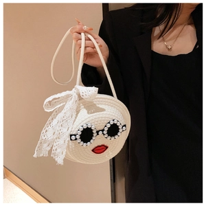 Detail of woven straw handbag featuring pearl sunglasses and lace bow decoration