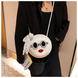 Detail of round woven straw crossbody bag with pearl sunglasses and lace bow accents
