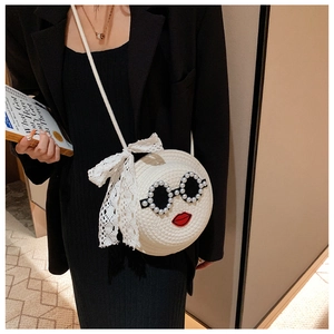 Detail of round woven straw bag with pearl sunglasses decor and lace bow accent
