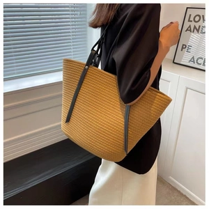 Detail view of woven cotton bucket bag in yellow featuring durable black leather shoulder straps