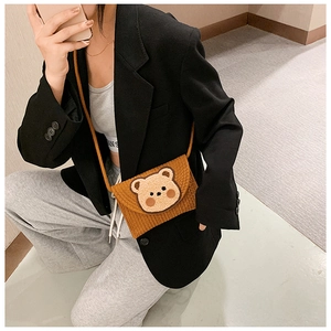 Detail of hand-woven brown straw phone bag featuring a cute 3D cartoon bear decoration