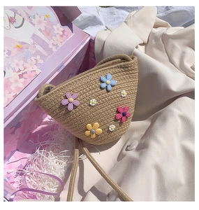 Détail du sac en paille tressée avec fleurs 3D colorées et fine bandoulière tissée