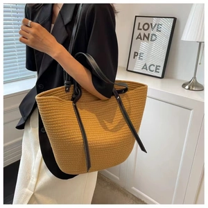 Detail of handwoven brown cotton bucket bag with black faux leather strap and contrast stitching