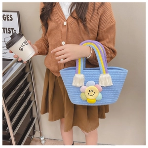 Close-up of light blue woven cotton bag featuring a plush rainbow sunflower and tassels
