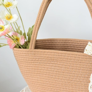 Detail of woven straw tote bag with spiral pattern and white stitching accents