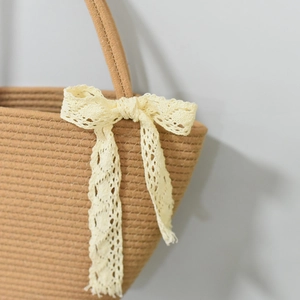 Close-up of woven cotton rope texture and yellow lace bow detail on the tote bag