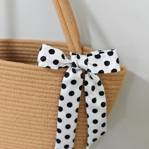 Close-up of woven straw tote bag with decorative black and white polka dot ribbon bow