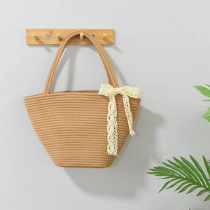 Retro woven straw tote bag with beige lace bow hanging on a wooden wall hook