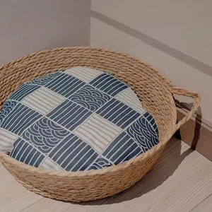 Detail of round rattan cat bed with a blue and white geometric patterned soft cushion