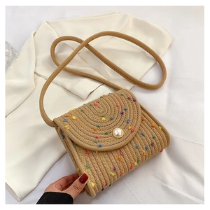 Dettaglio borsa a tracolla in paglia intrecciata a mano con pois colorati e bottone perla