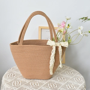 Detail of hand-woven cotton rope tote bag with lace bow and floral accent