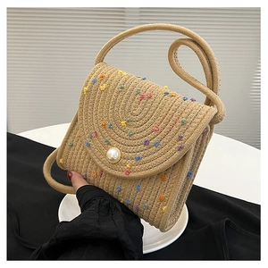 Dettaglio della borsa a busta in cotone beige intrecciata a mano con pois colorati e perla