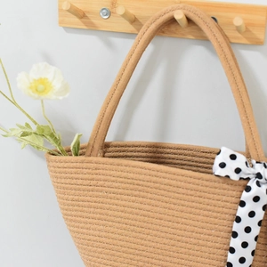 Detail of hand-woven straw tote bag with elegant black and white polka dot ribbon accent