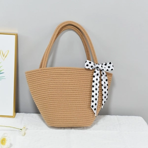 Close-up of brown woven straw tote bag with black and white polka dot ribbon bow detail