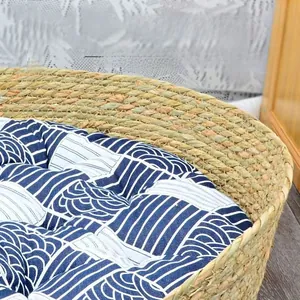 Close-up of durable hand-woven straw cat bed featuring a thick blue wavy pattern cushion