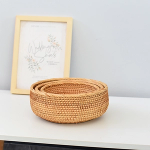 Detailed view of three-piece natural rattan round storage baskets in a home setting