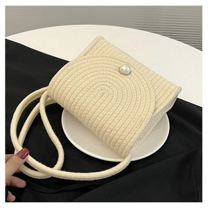 Dettaglio borsa in cotone intrecciato panna con chiusura a perla su vassoio circolare bianco