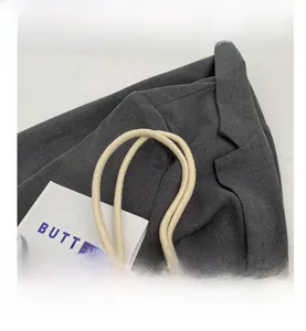 Detail of a beige canvas bag showing the thick braided rope shoulder strap texture